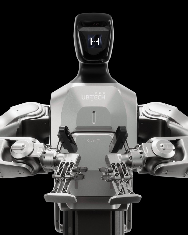 The UBTECH Cruzr Y1 industrial humanoid, head and dual arms, on a black studio field.